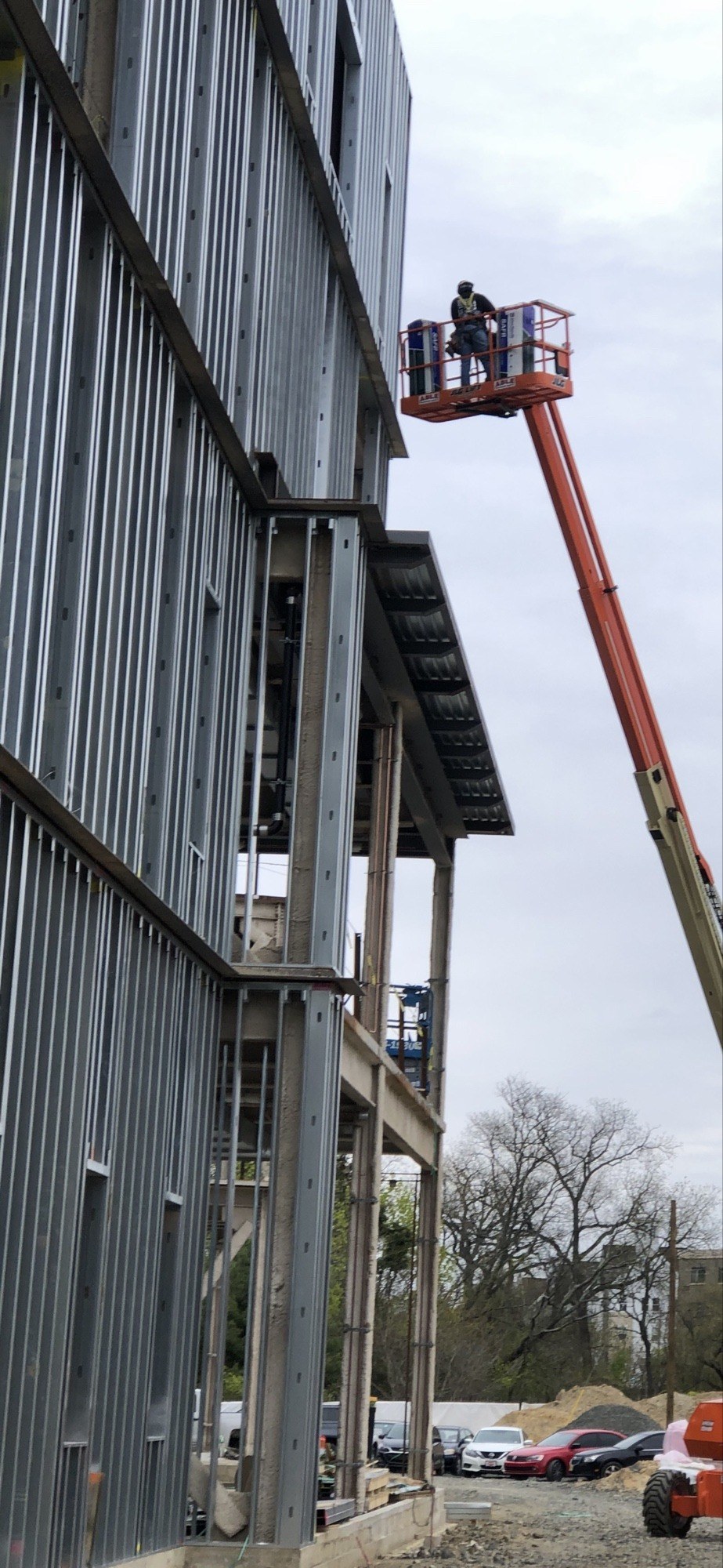 Crew member on a boom lift installing steel framing on a commercial building elevation