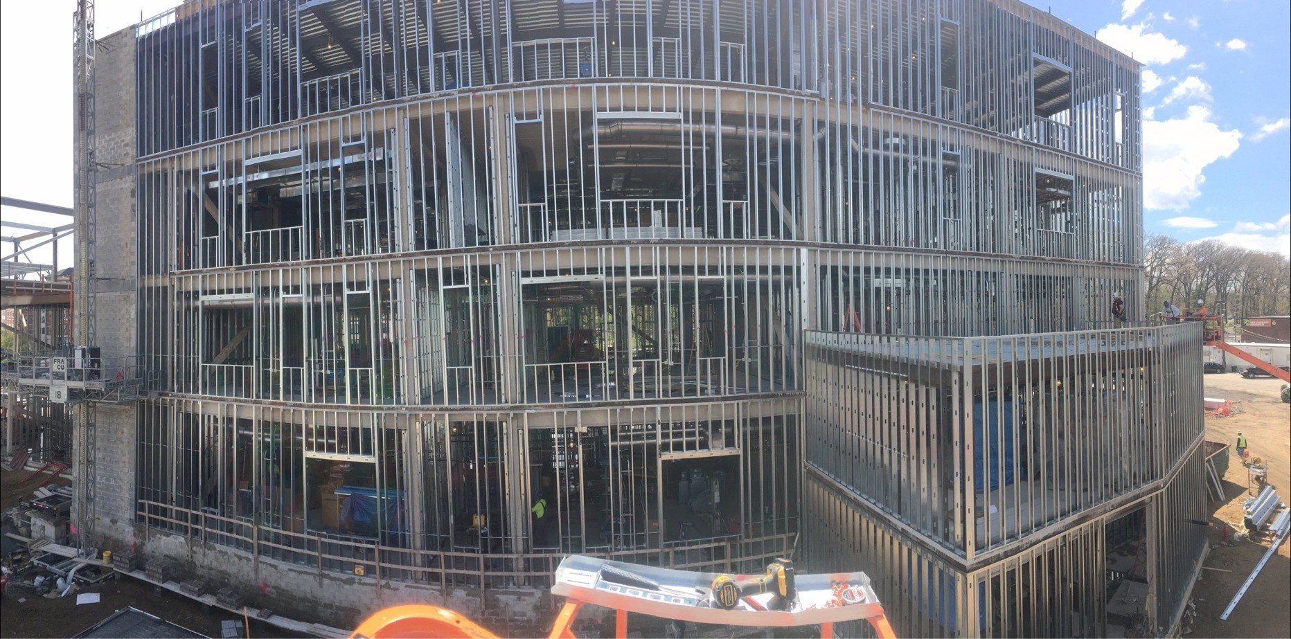 Large-scale commercial building under construction with steel stud framing and a curved facade
