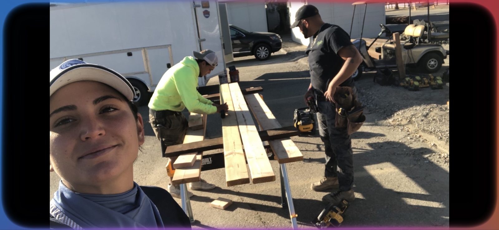 Wilson's crew member takes a selfie while two teammates cut and prep lumber on site next to the equipment trailer