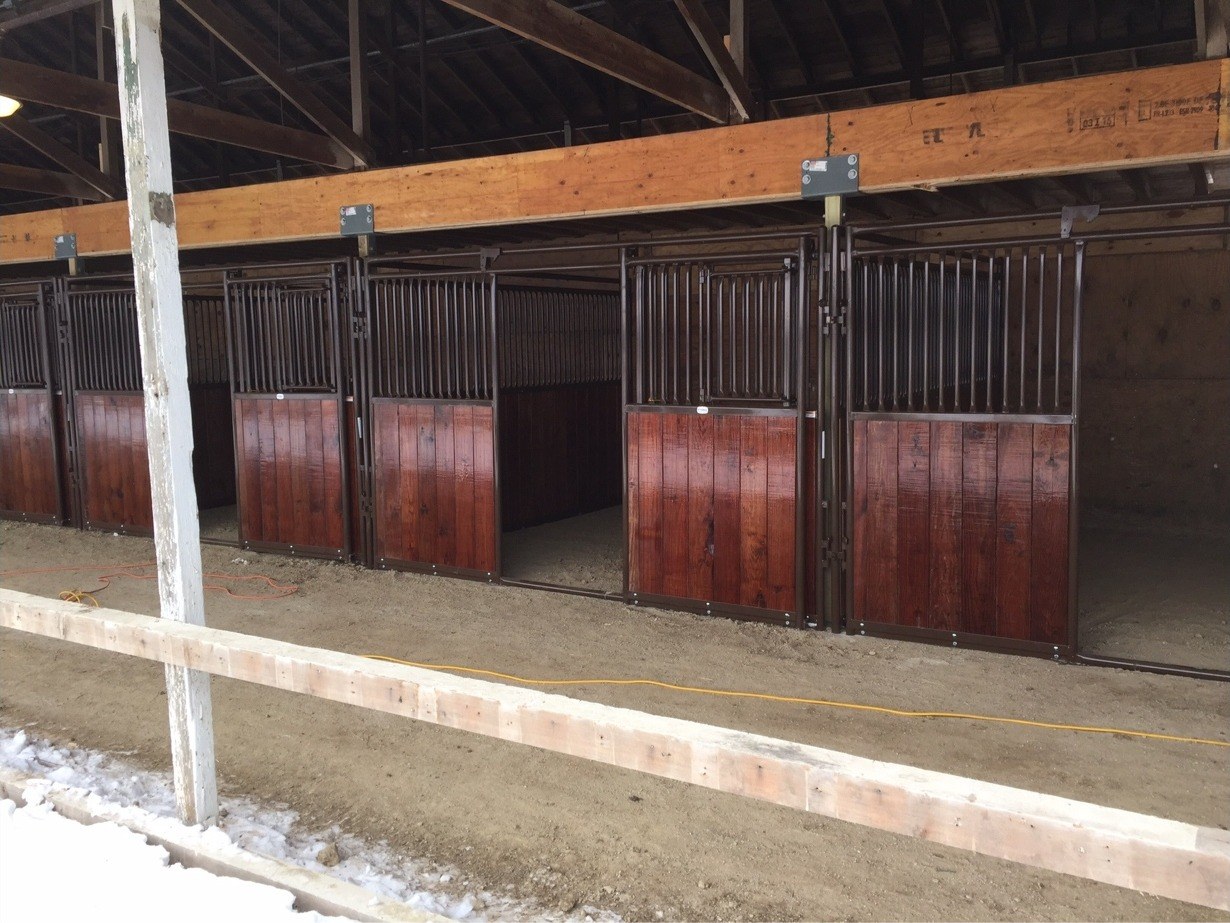 Interior of a custom horse barn showing finished wood stall dividers and support beams