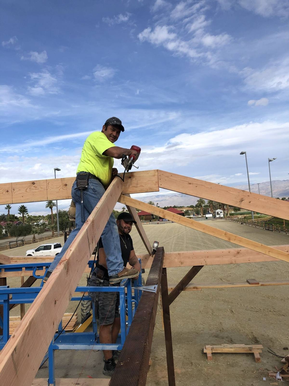 Two crew members securing roof trusses on a custom build