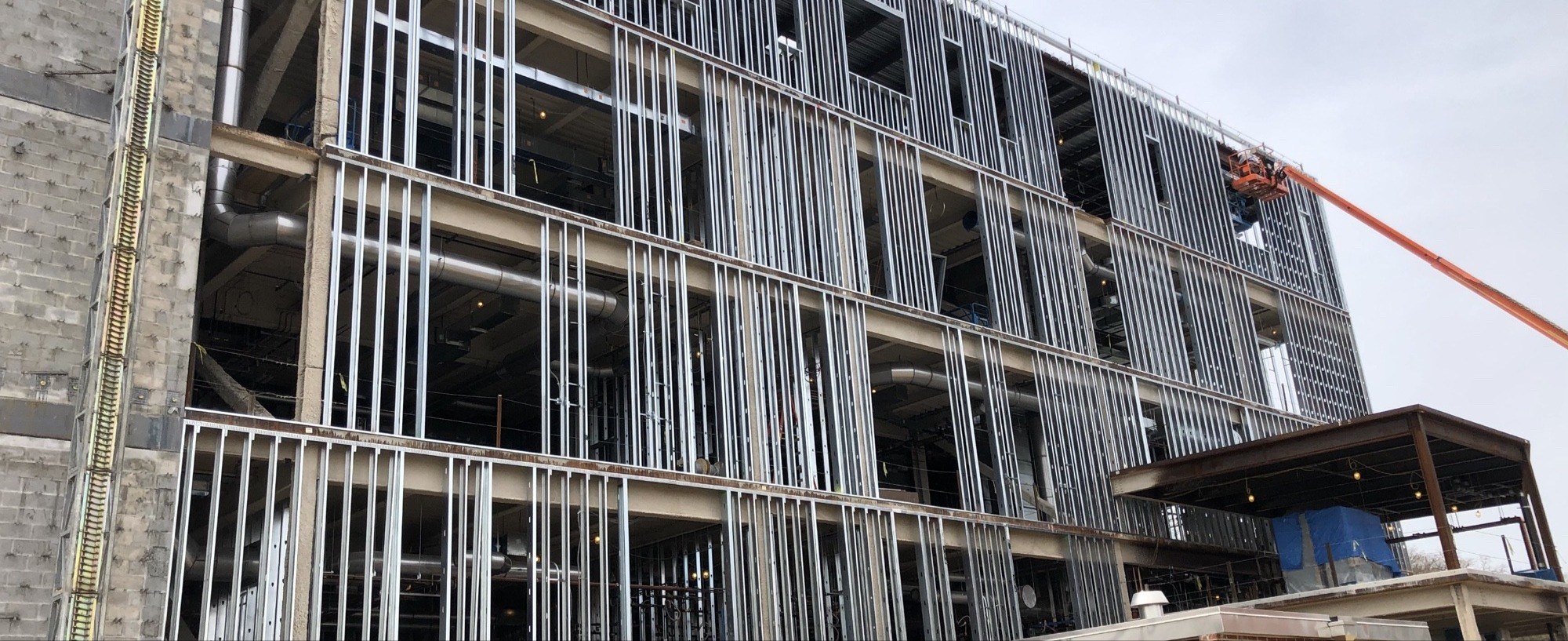 Multi-story commercial building steel framing with a boom lift reaching the upper floor
