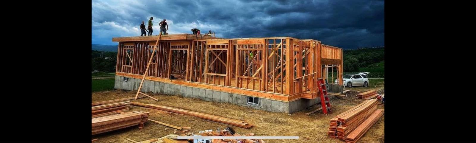A Wilson's Custom Construction crew framing a new home under a dramatic sky