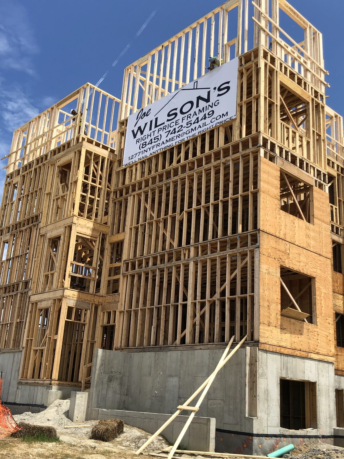 Joe Wilson's Right Price Framing job site sign posted on a multi-unit building under construction
